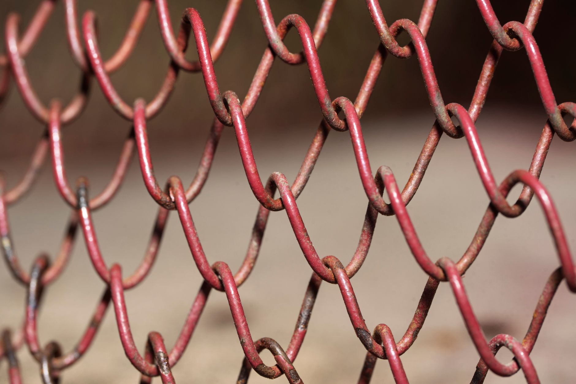 Detailed view of a red rusty chain link fence, highlighting texture and pattern.